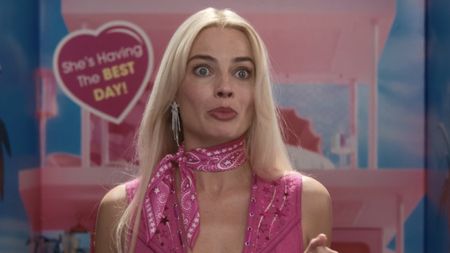 Margot Robbie's Barbie standing in front of life-sized box inside Mattell in Barbie