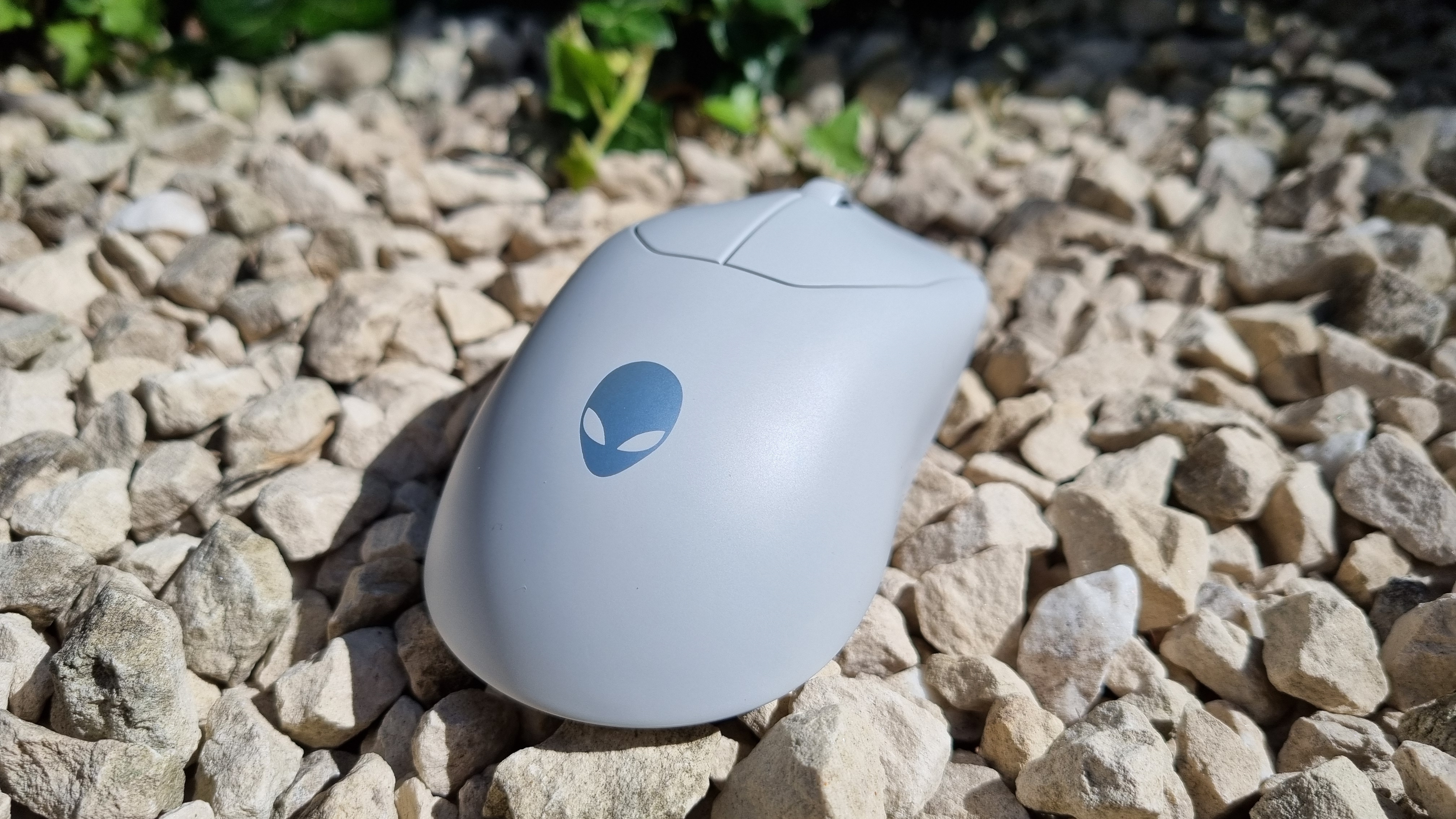The Alienware Pro Wireless gaming mouse on white gravel, showing the silver Alienware logo
