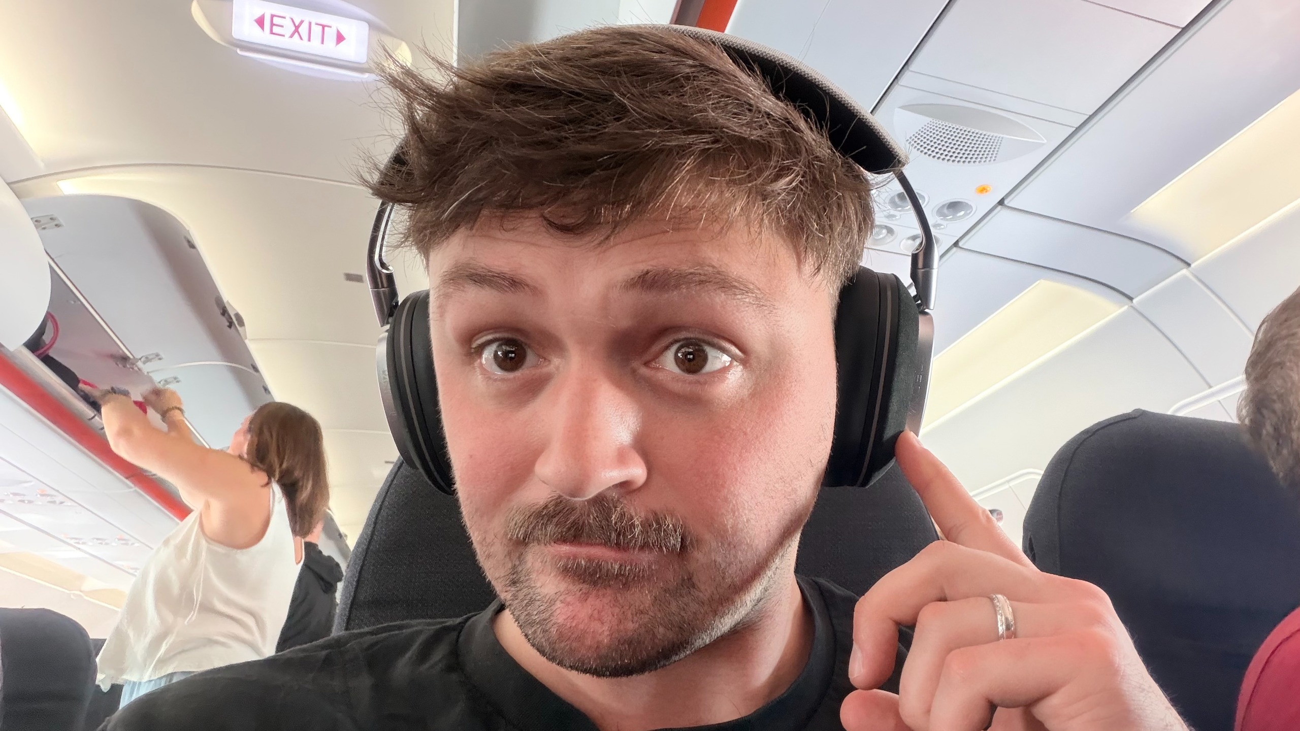 A selfie photo of Editor Peter Wolinski wearing a set of the Noble Audio FoKus Artemis onboard a plane.