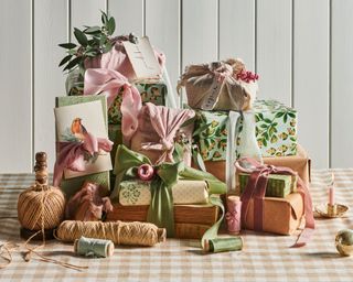 Wrapped christmas presents in brown and colorful pastel paper, decorated with ribbons and accessories, string, christmas foliage