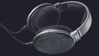 A pair of Sennheiser HD 650 headphones lying sideways on a black background