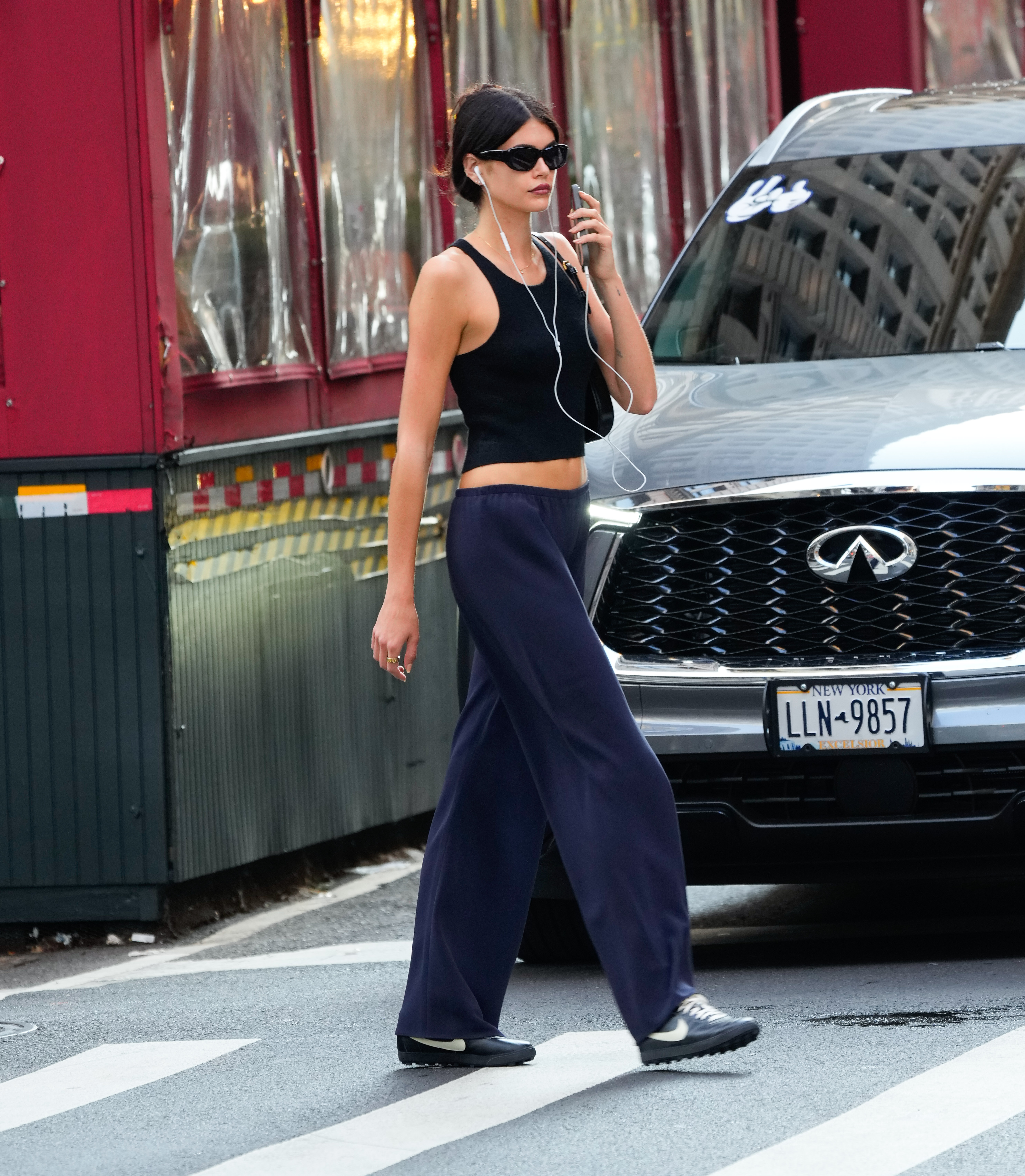 Kaia Gerber walking around new york city wearing a cami tank top and blue pants