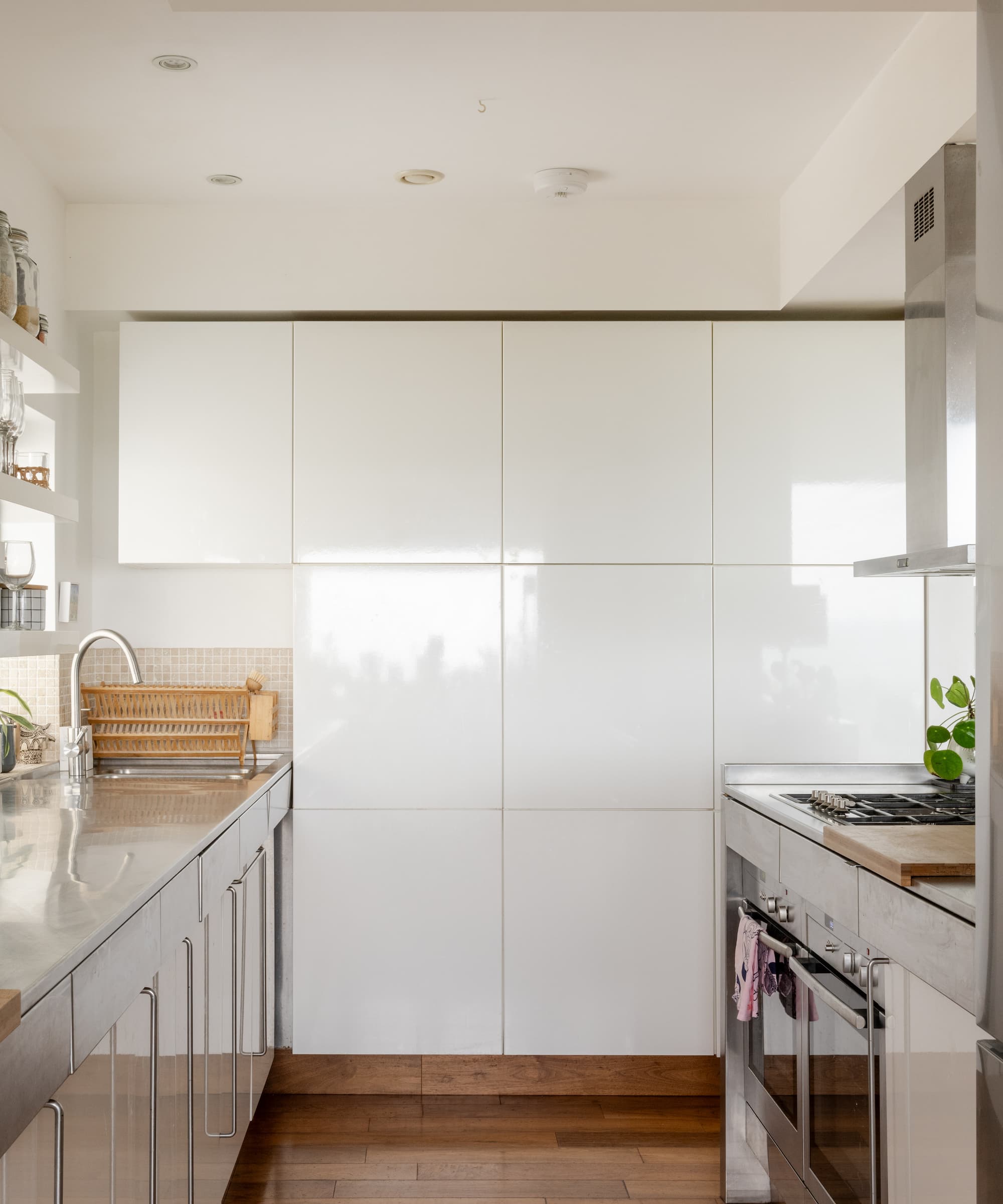 A narrow white kitchen with white cabinets