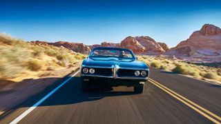 Man driving vintage car through desert