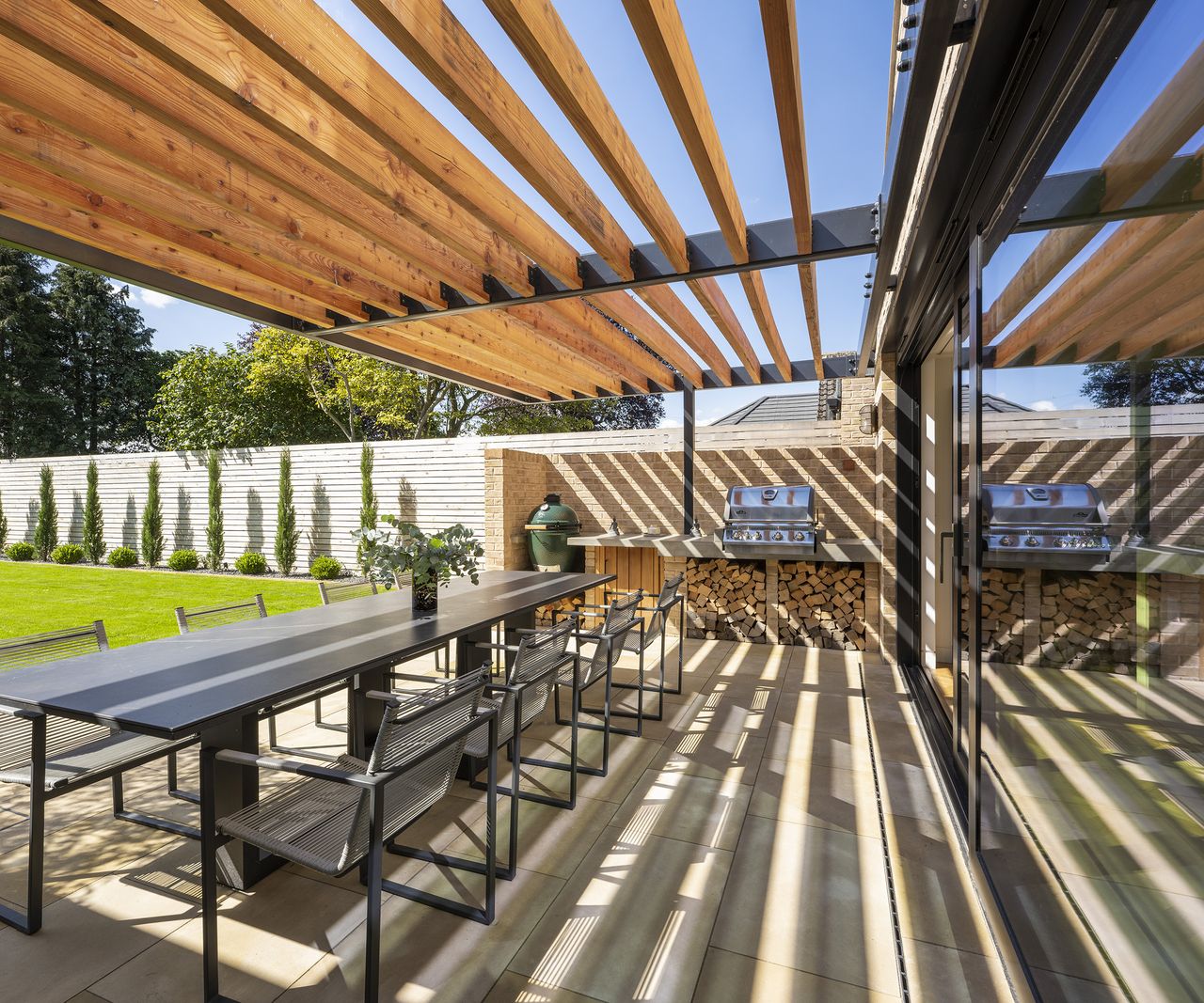 Covered patio area with outdoor kitchen and log storage