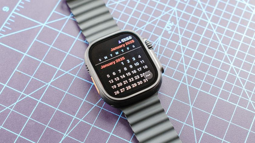 Apple Watch Ultra 2 in Jet Black sitting on a gridded cutting mat showing the 2025 calendar view on the screen