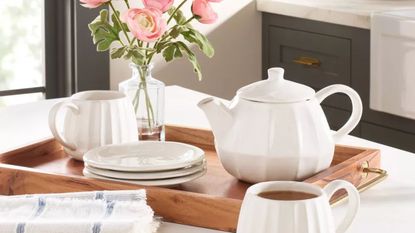 White teapot, saucers and mugs on a wood tray