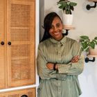 A picture of Shantae Duckworth - a woman wearing a green shirt smiling into the camera, standing next to a woven closet