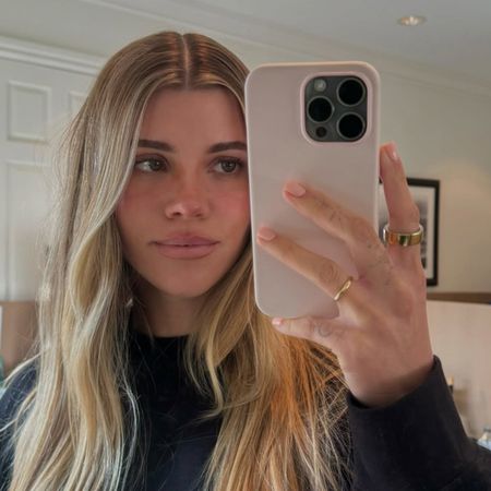 Sofia Richie Grainge wearing a black crewneck sweatshirt in a mirror selfie with her pink phone case.