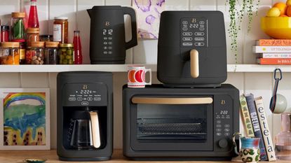 Four matte black small kitchen appliances stacked together in kitchen