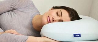 A woman with dark hair closes her eyes as she lays her head on the Casper Snow Pillow