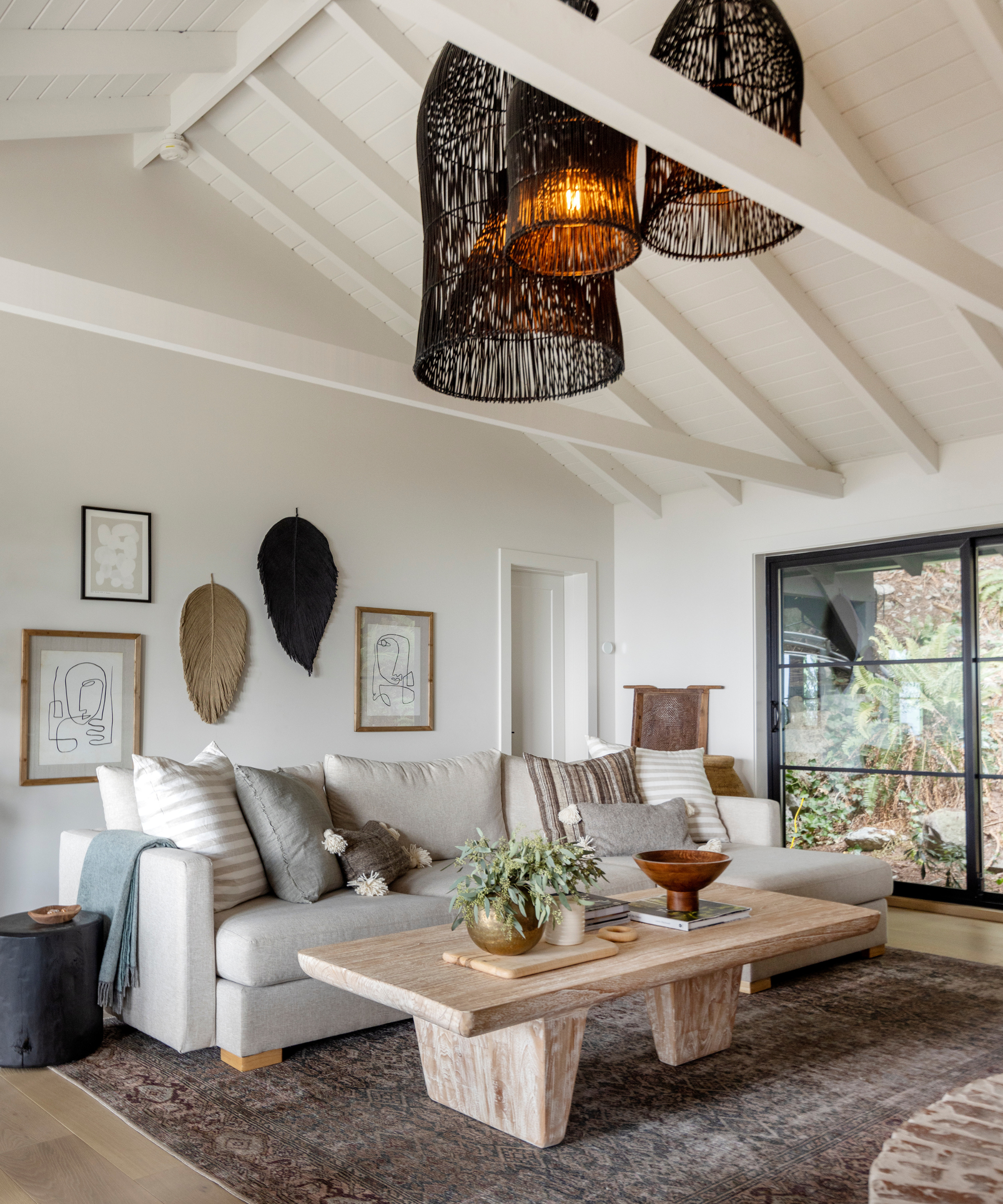 A white living room with lofted ceilings and large statement black light fixtures