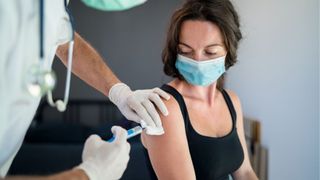 woman in face mask receiving vaccine