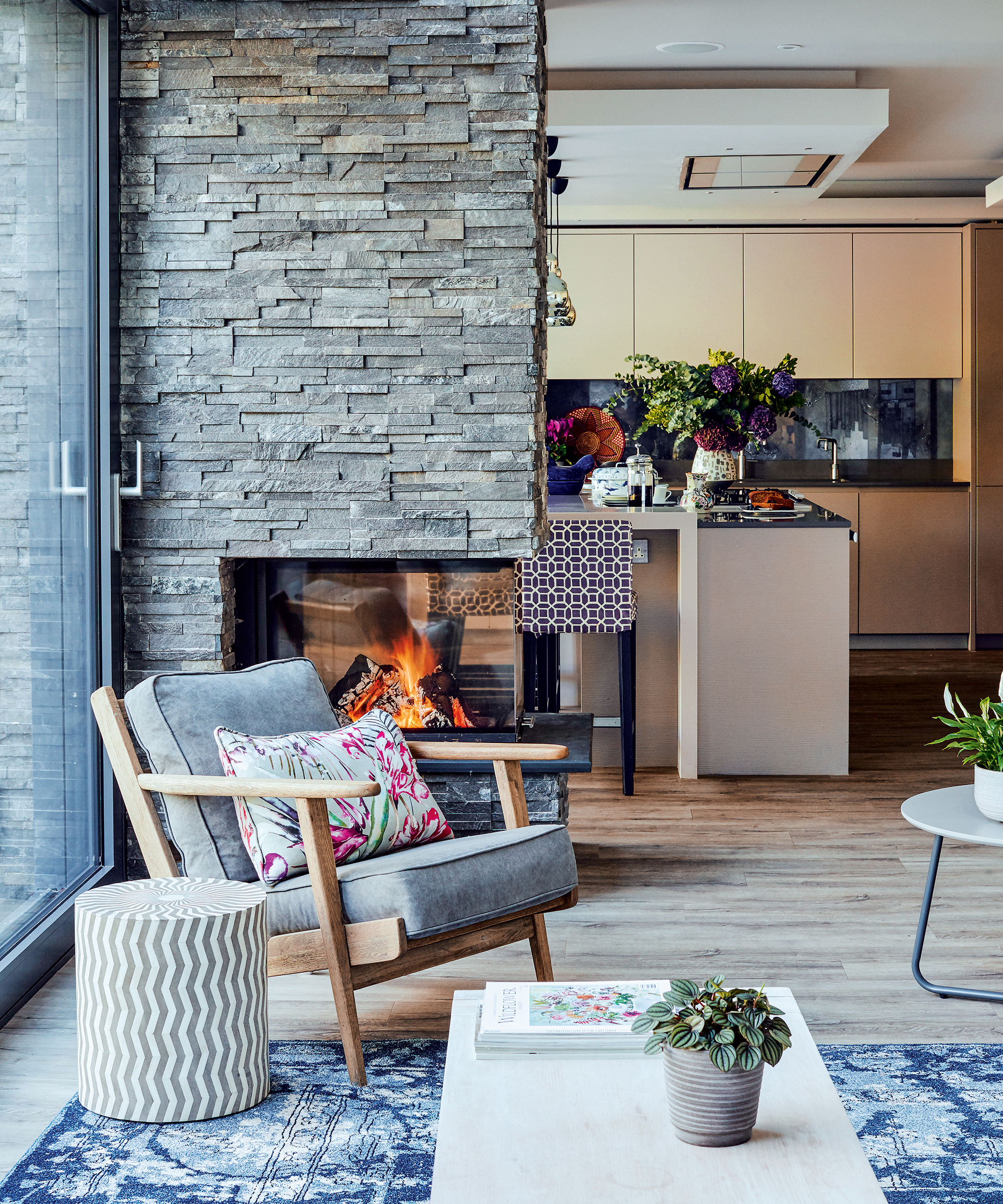 Open plan space with kitchen, stone wall and wood floor