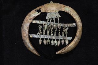 The mounted boars' tusks are adorned with two bronze strips and bronze pendants. If the ornament were placed on a horse's chest, the pendants would have jingled against the bronze strips when the horse moved.
