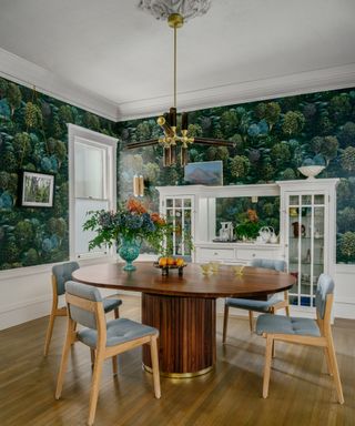dining room with leaf print teal wallpaper and table with broad base