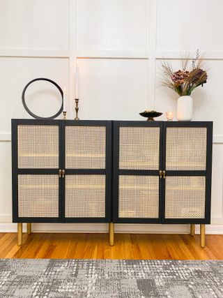 rattan fronts on a black cabinet with gold legs and candles on top