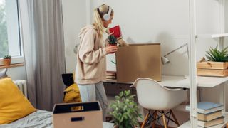 College student unpacking box in dorm room
