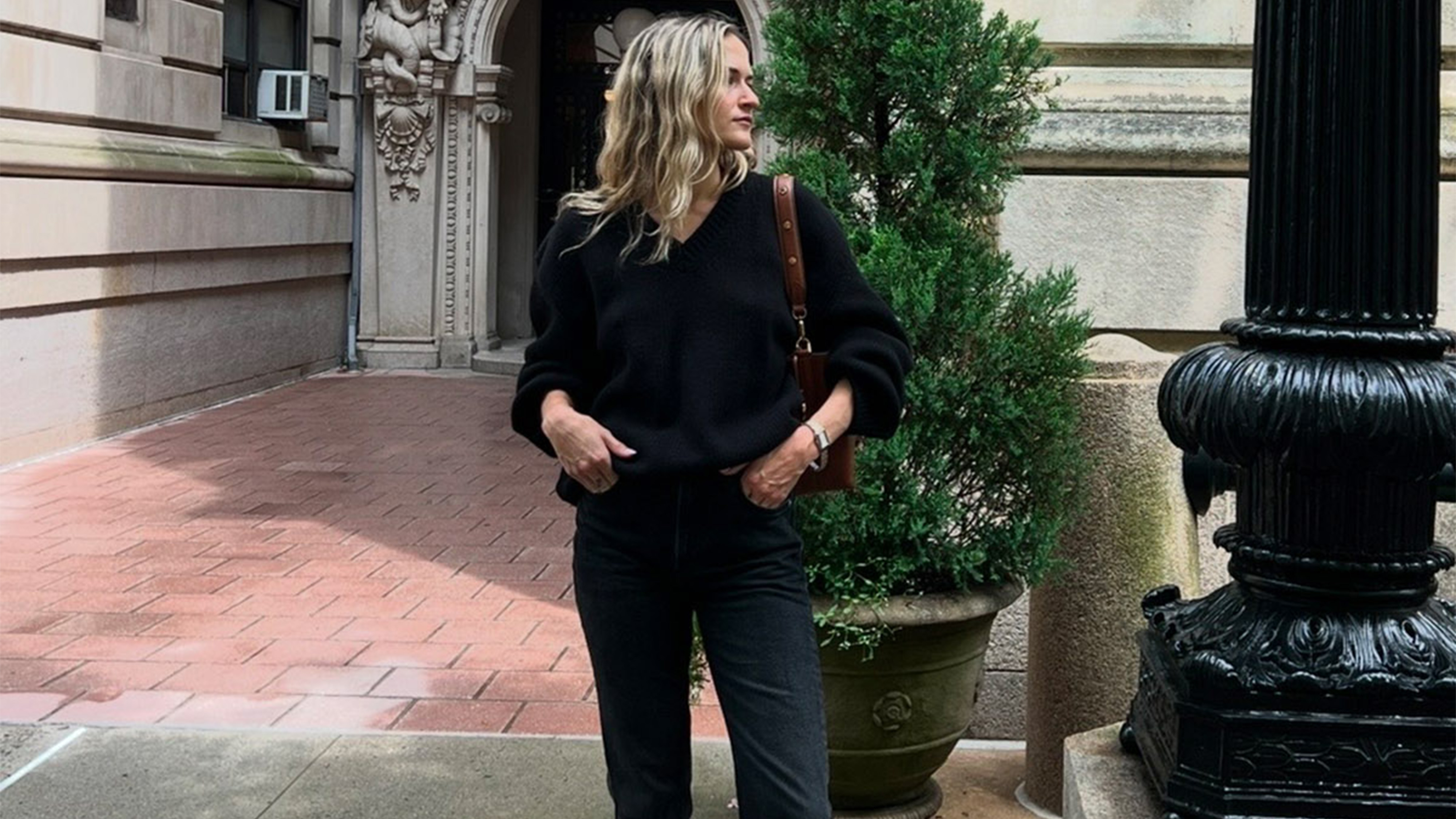 eliza wears black stovepipe jeans and a black sweater.