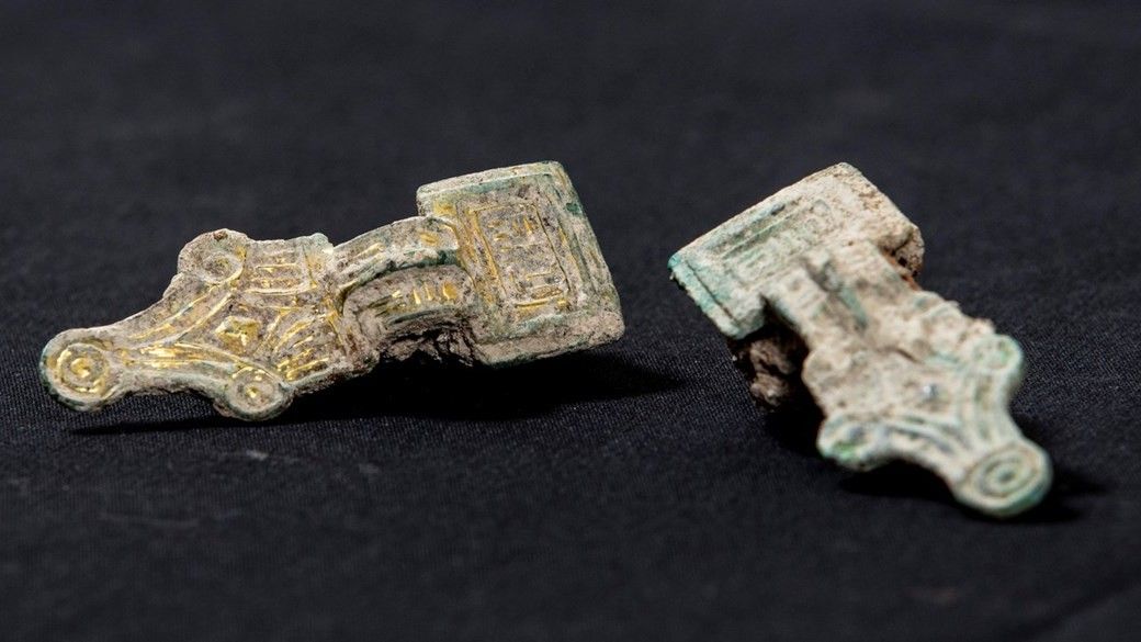 Here we see 2 ornate brooches that were found in an Anglo-Saxon grave. These ones are decorated with gold. One side of is rectangular and the other side looks like a crown with a very high middle point.