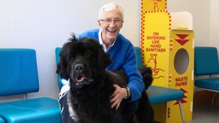 Paul O'Grady hugs a large black Newfoundland dog in For the Love of Dogs series 11.