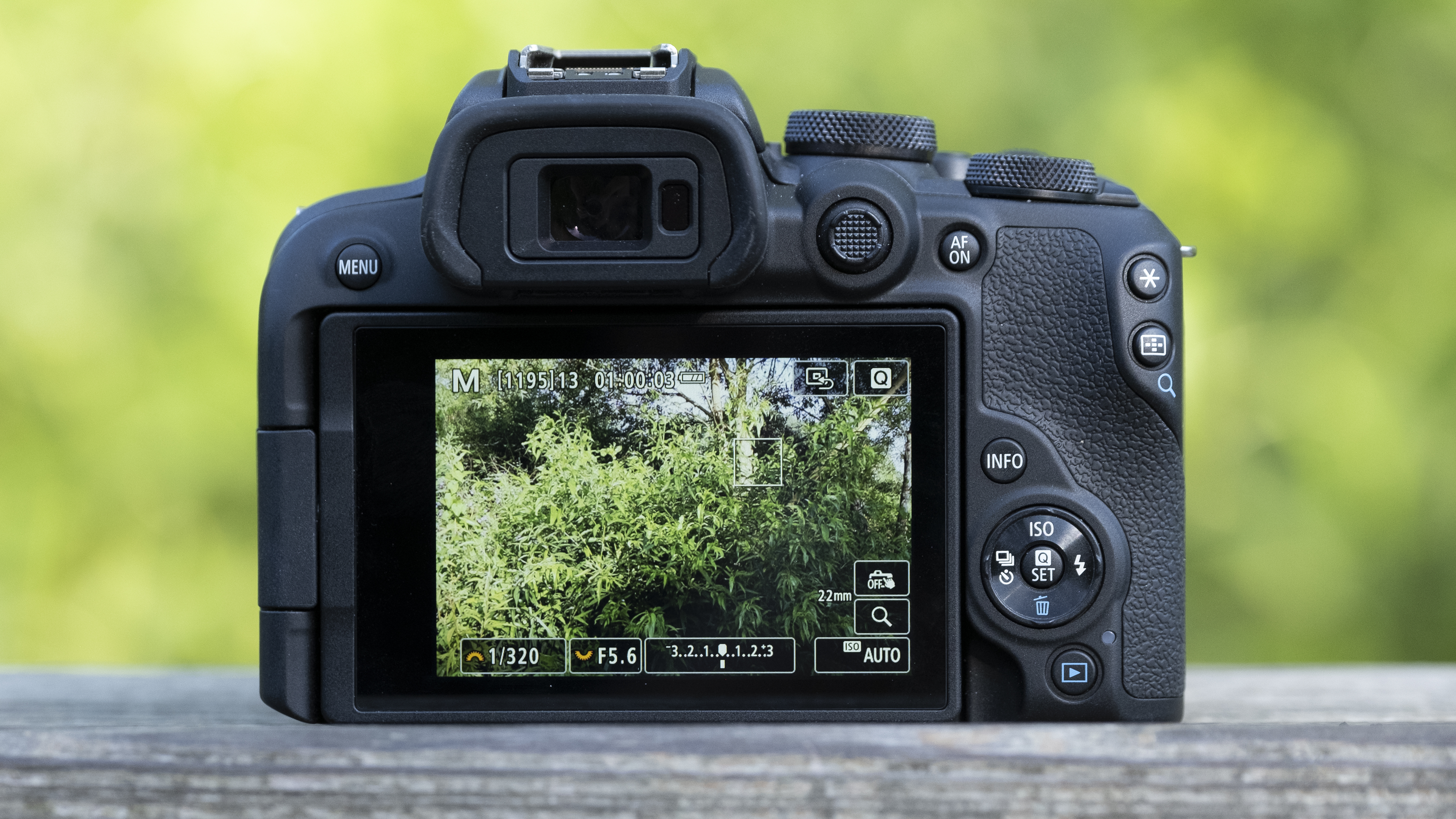 The Canon EOS R10 camera sitting on a wooden bench