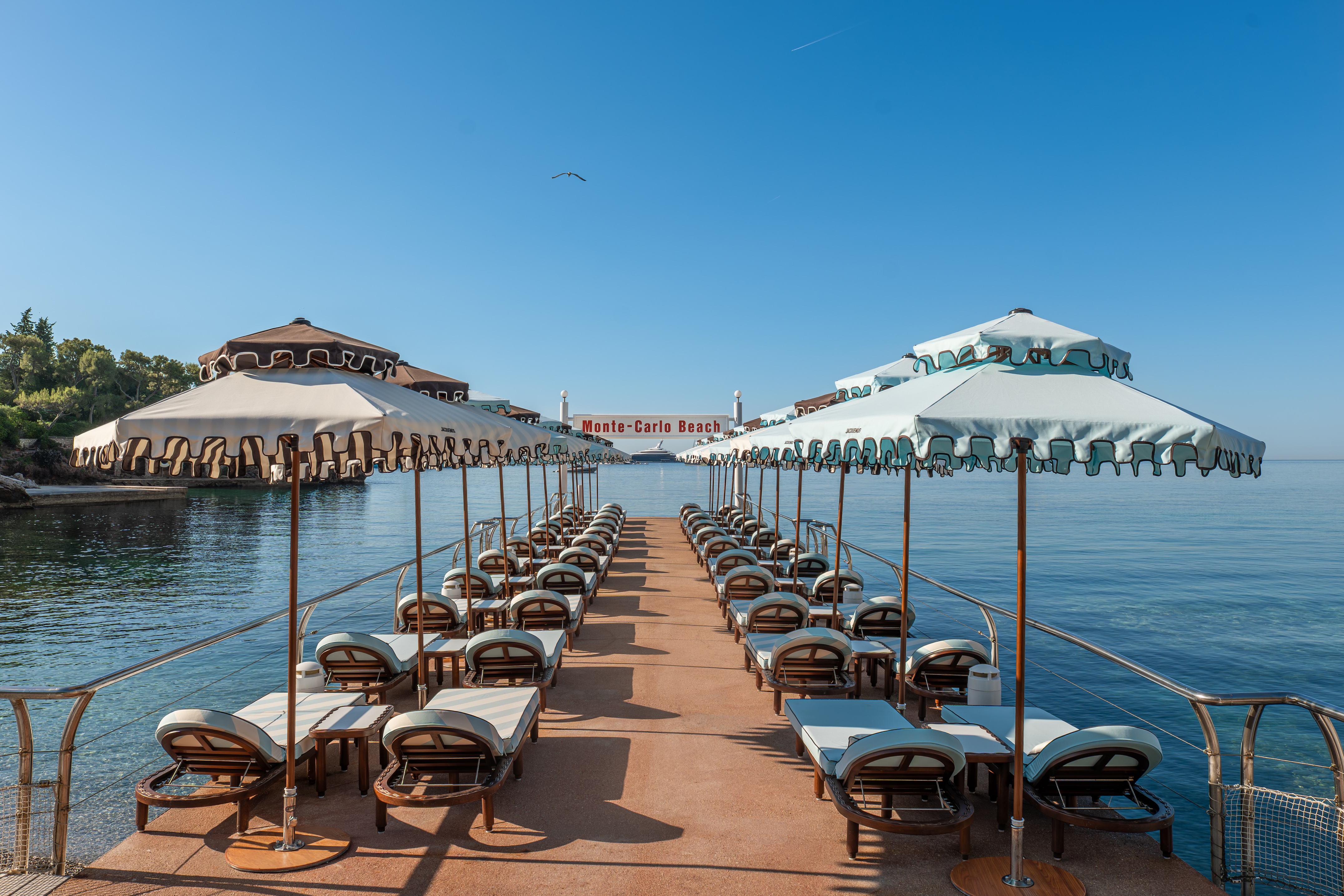 An image of bespoke parasols and sunbeds by Jacquemus that line a jetty at Monte-Carlo Beach hotel in Monaco.