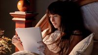 Dakota Johnson as Lowen reading a pile of paper in Verity. 