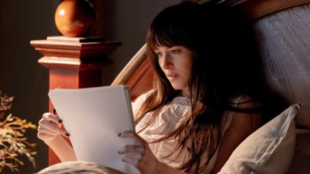 Dakota Johnson as Lowen reading a pile of paper in Verity. 