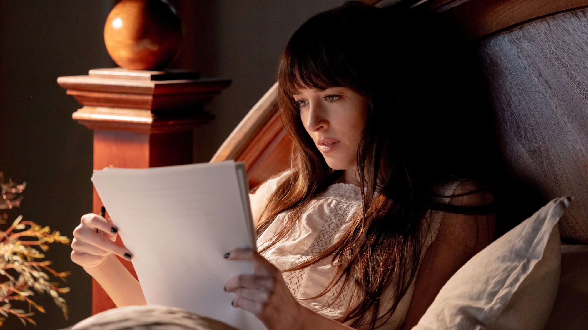 Dakota Johnson as Lowen reading a pile of paper in Verity. 