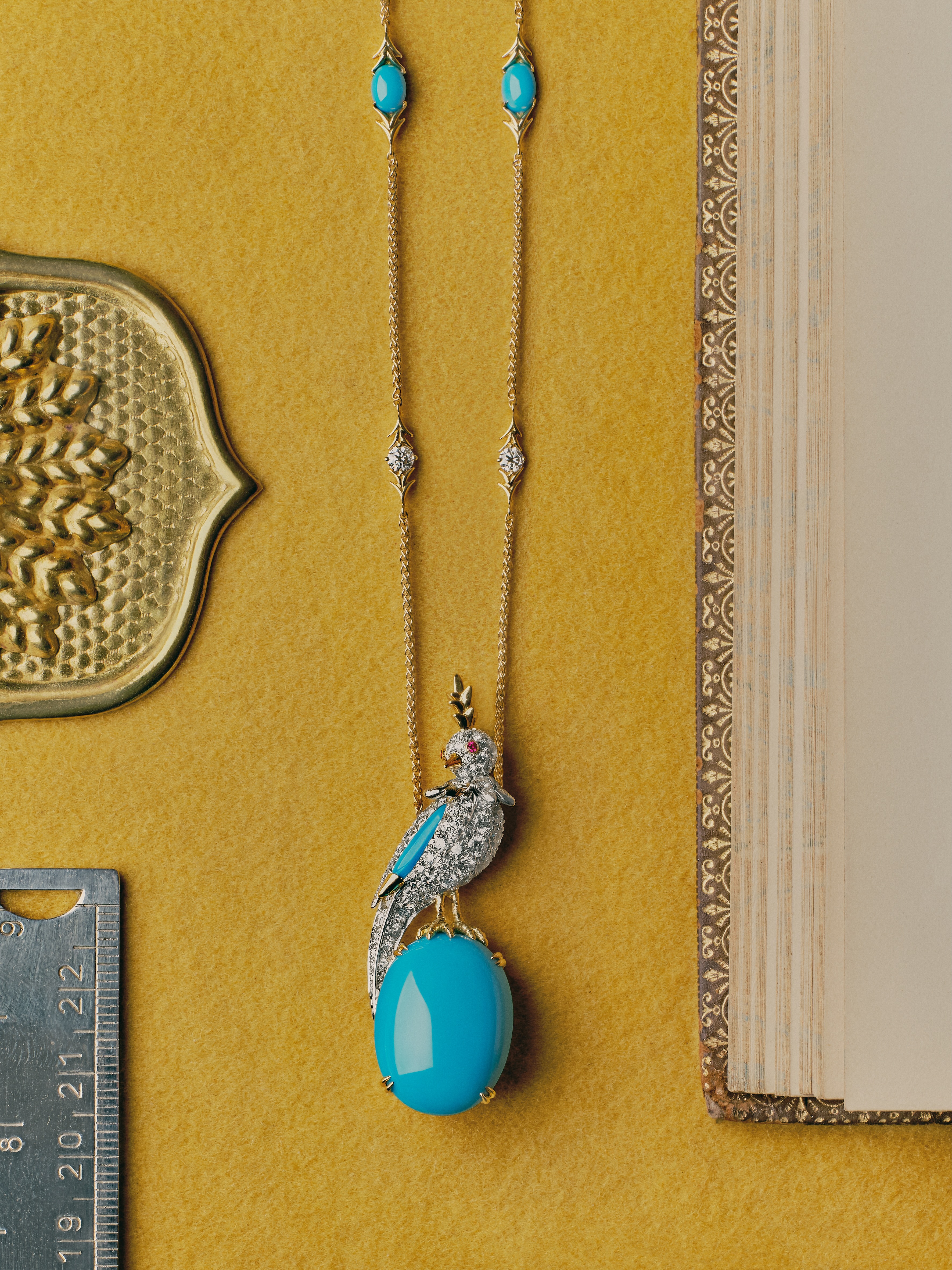 Turquoise and diamond pendant necklace photographed on a yellow background