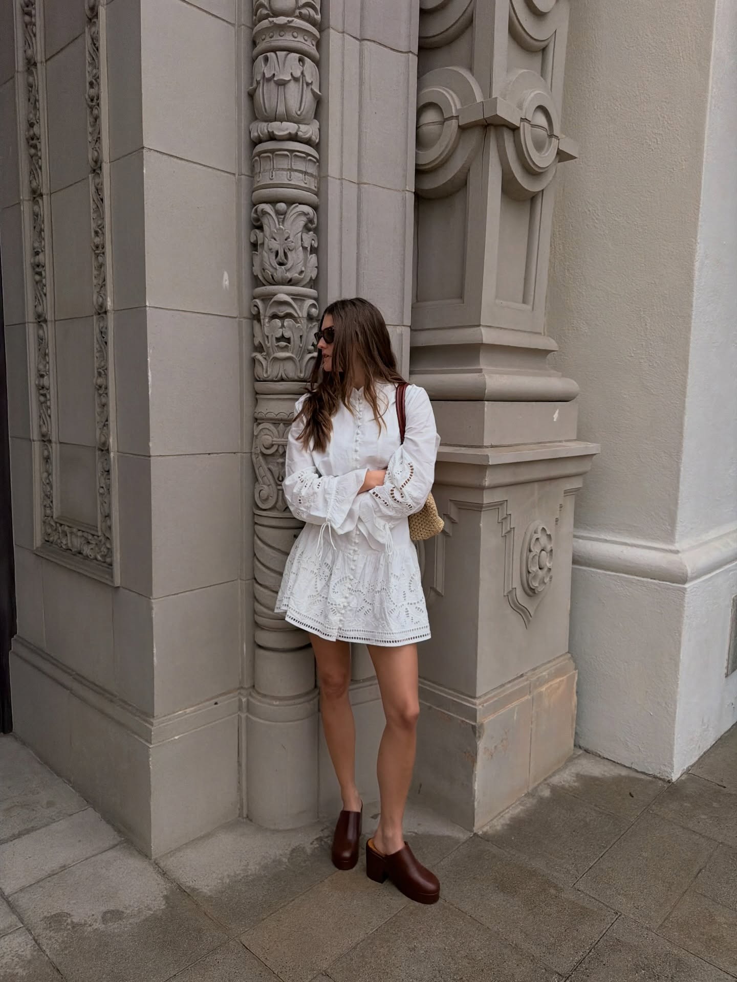 Woman wears white dress and brown clogs