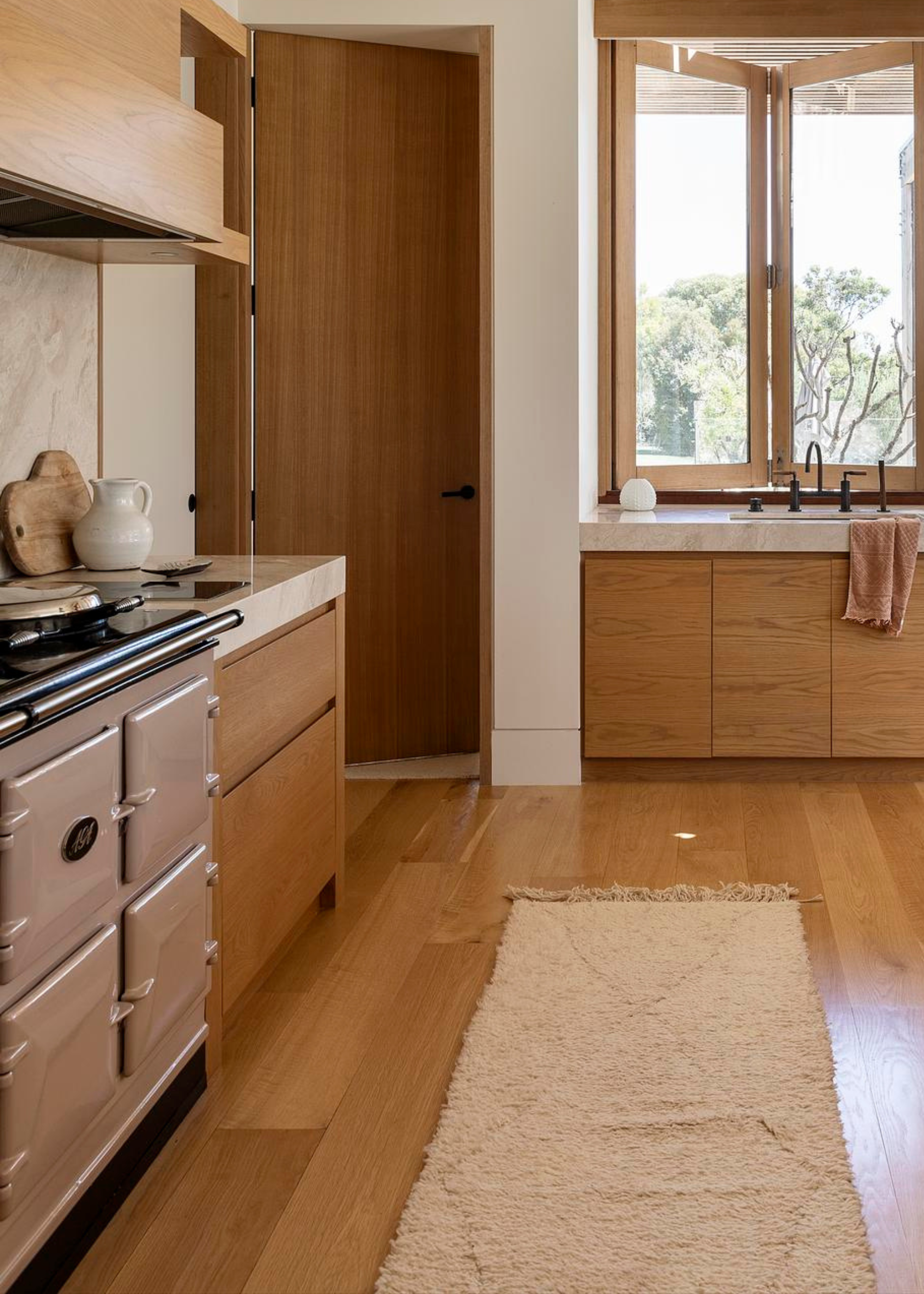 sleek wooden modern aga kitchen with a pink aga oven