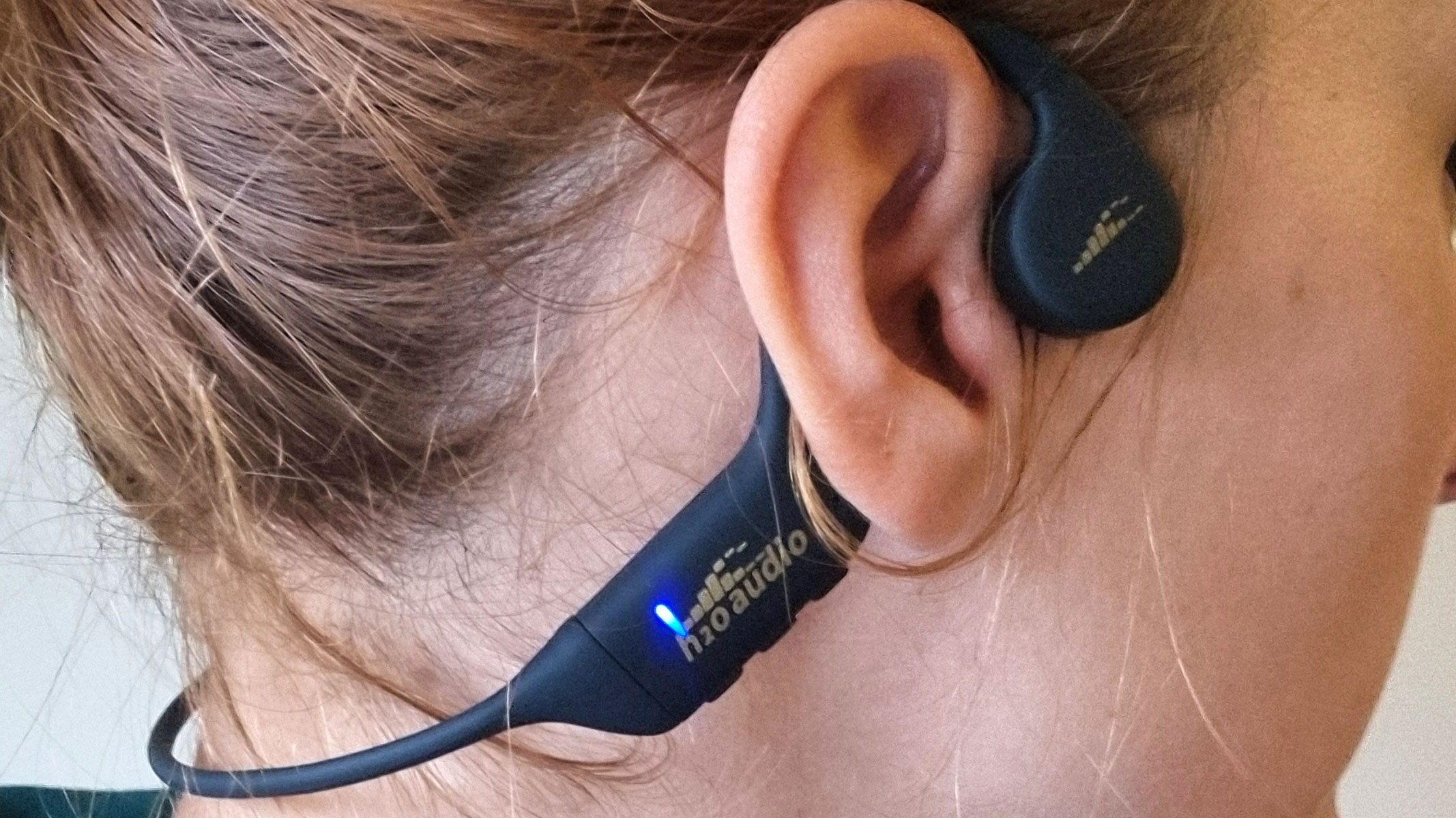 a close-up picture of our reviewer testing the H20 Audio Tri 2 Pro headphones