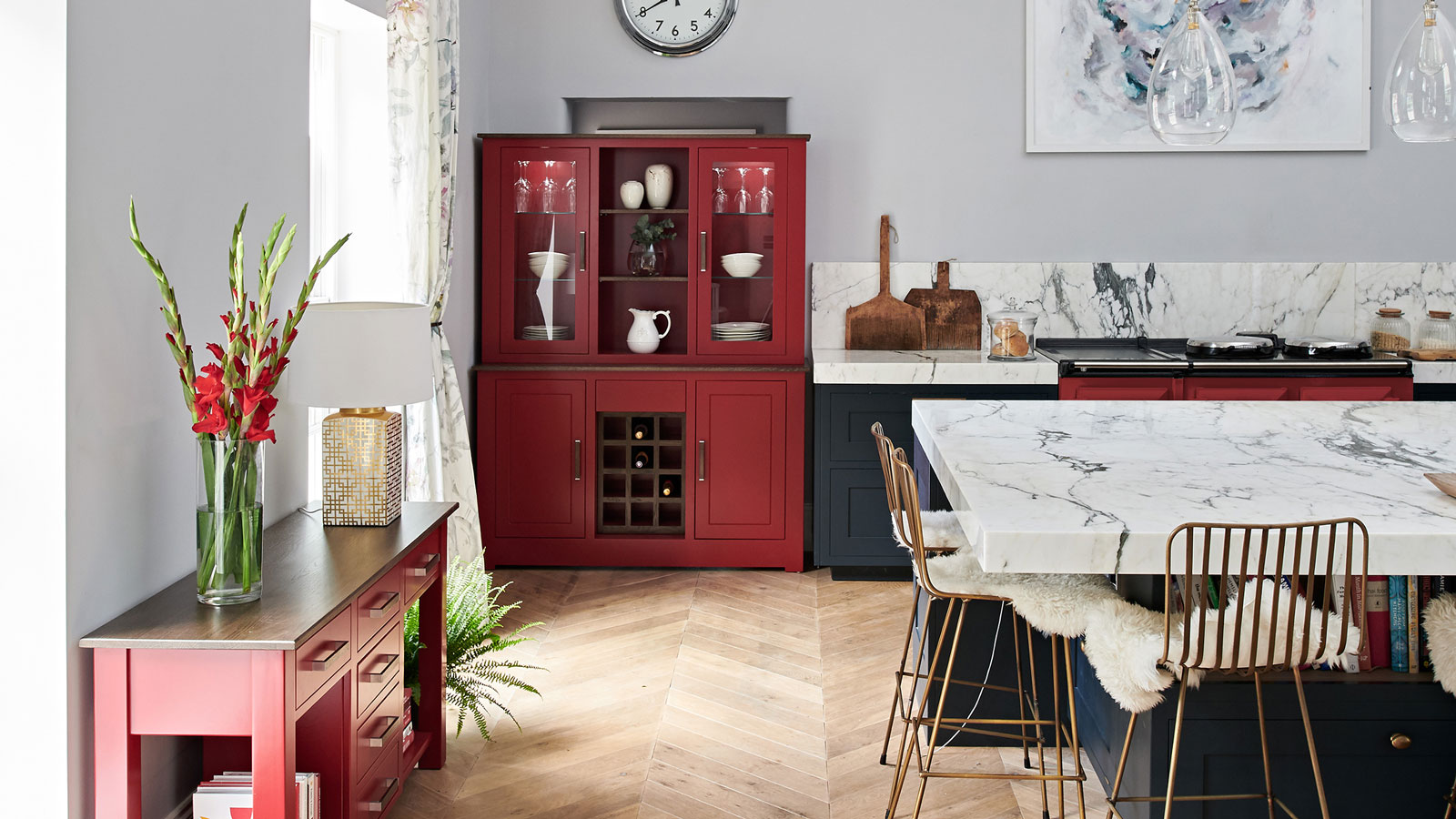 black and red kitchen with wooden herringbone flooring and marble worktops