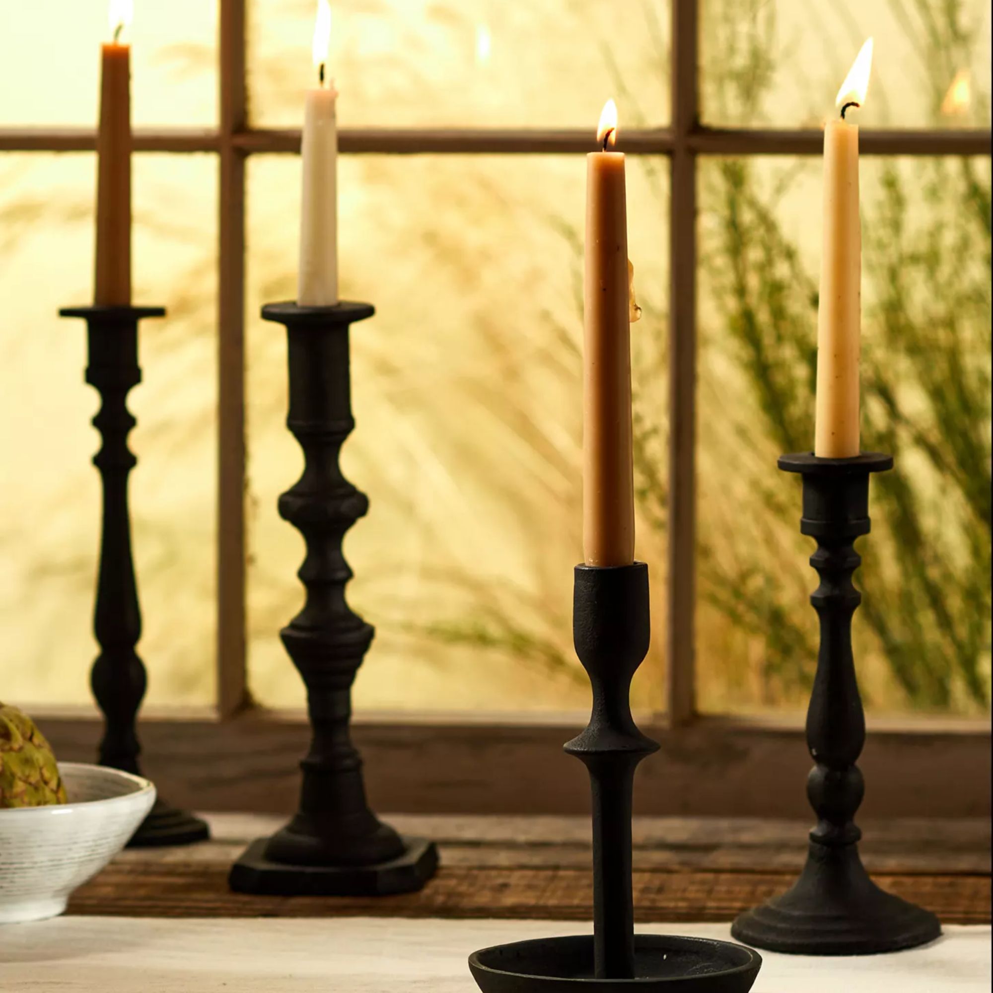 four black candle holders with lit candles