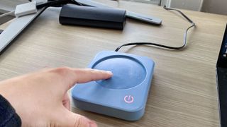 A finger touching a hot mug warmer