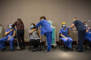 Health care workers get vaccinated with the Pfizer-BioNTech COVID-19 vaccine in Portland, Oregon. Slowing the spread of a new COVID-19 variant in the U.S. will be critical to allow time to increase vaccination coverage and achieve higher immunity against the virus, the CDC says.