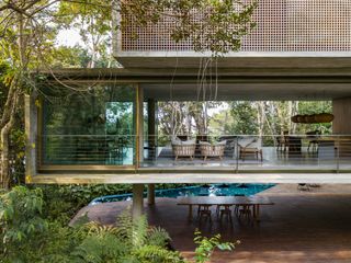 Elevated seating area in forest with dining table beneath also