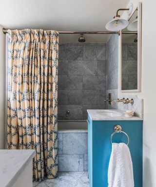 Bathroom with grey marble tiles and blue freestanding sink unit