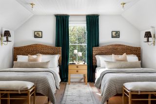 Bedroom with twin double beds with rattan headboards, wall lights and lights overhead, plus shared bedside table with table lamp