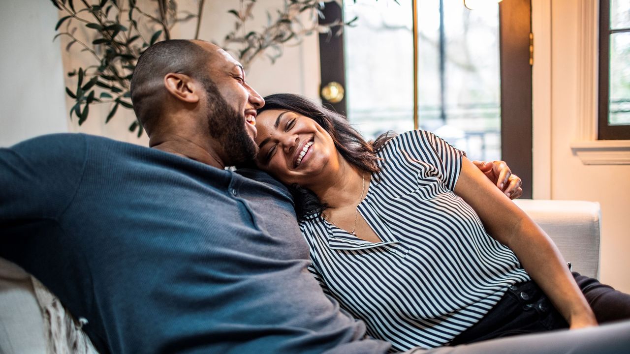 A husband and wife lounge comfortably on a couch. 