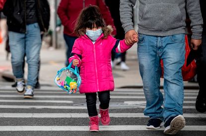 A girl, wearing a mask, walks down a street in the Corona neighborhood of Queens on April 14, 2020 in New York City.