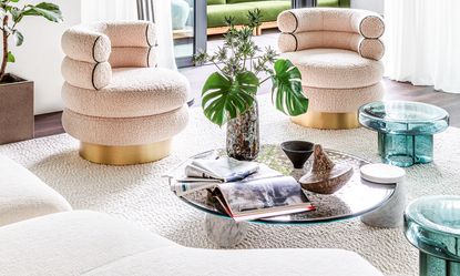 glass coffee table in a white living room with white accent chairs