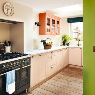 pink kitchen with cabinets and a range cooker