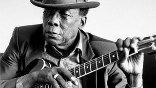 Blues singer John Lee Hooker wearing hat, posing w. his Gibson ES-335 at home, October 7, 1990. 