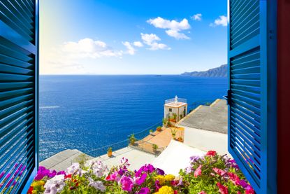 View through bright blue shutters of a cirulean blue seak and white washed Greek houses
