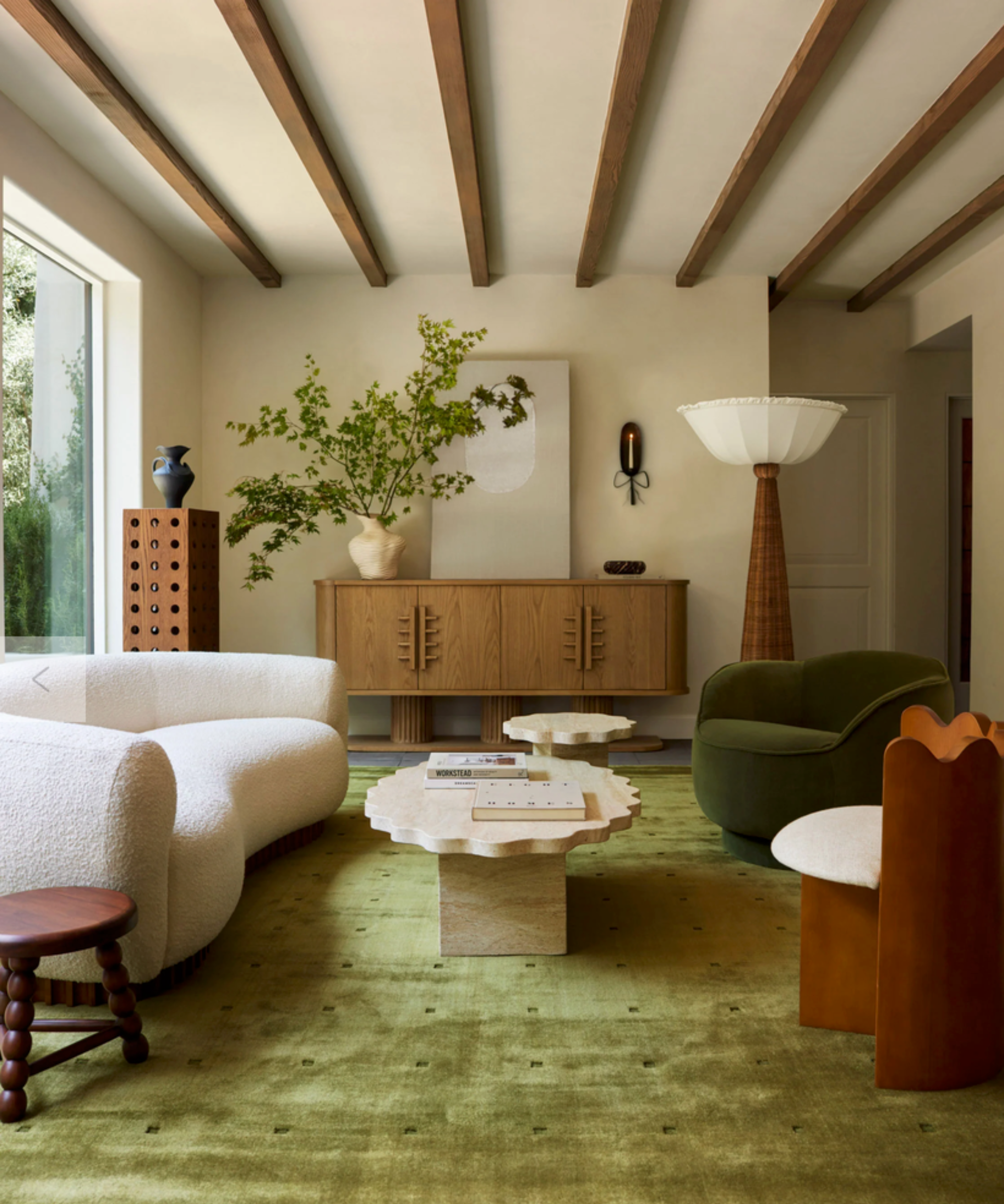 White curved sofa in living room with green rug