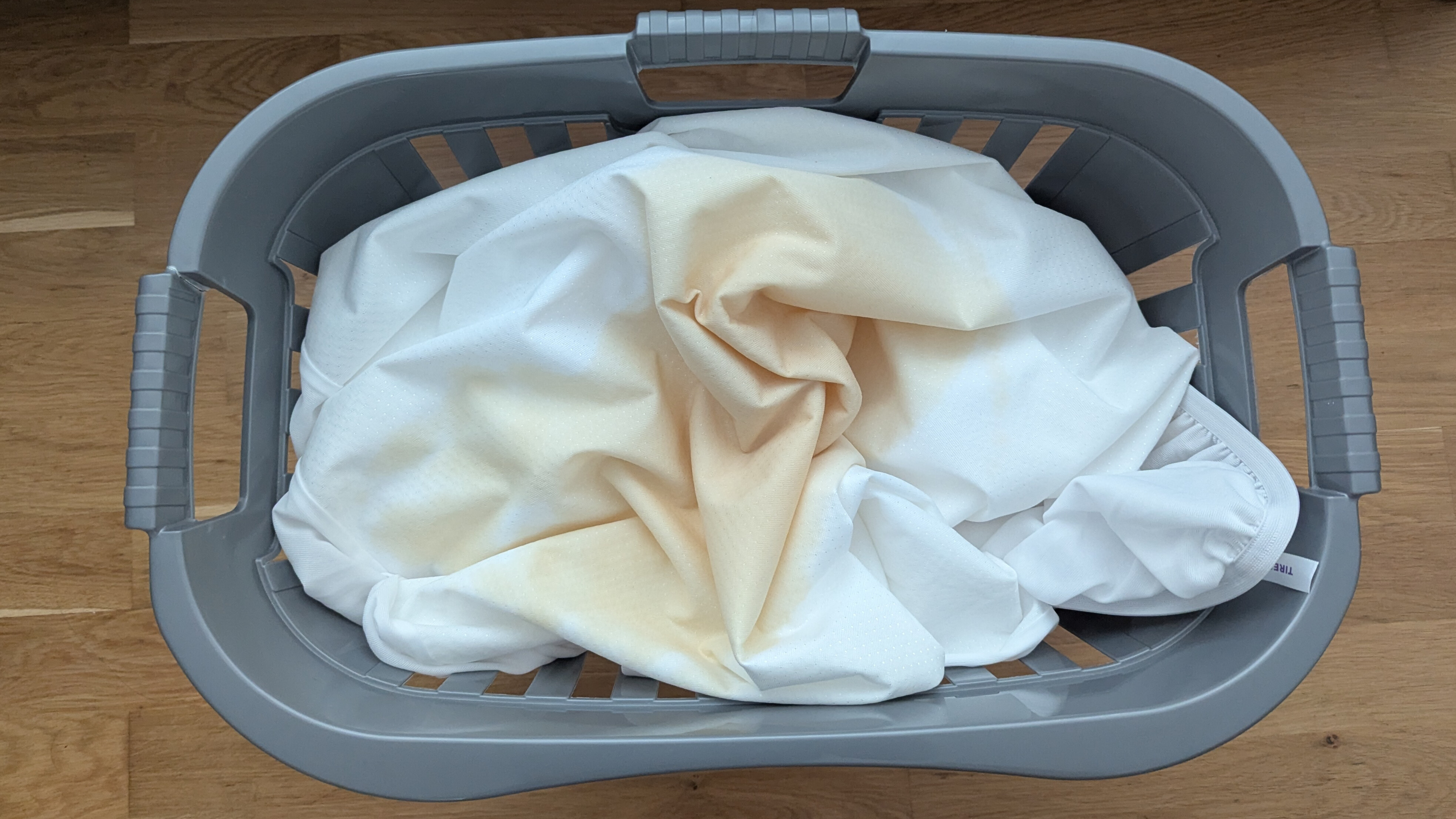 A dirty mattress protector in the laundry basket