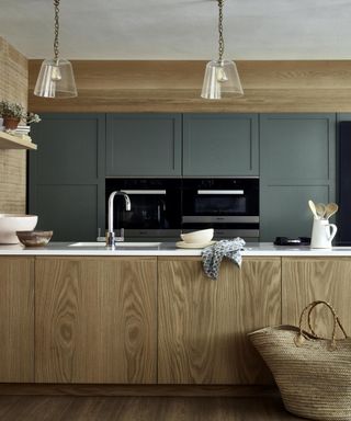 Modern wood kitchen, green floors with installed double oven behind kitchen island